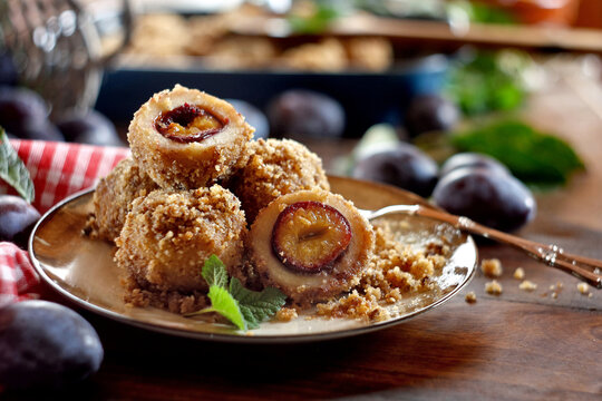 Homemade sweet plum dumplings with breadcrumbs, walnut and cinnamon on a wooden background