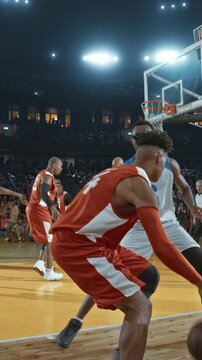 Basketball Player Dribbling Past a Defender in a Packed Arena