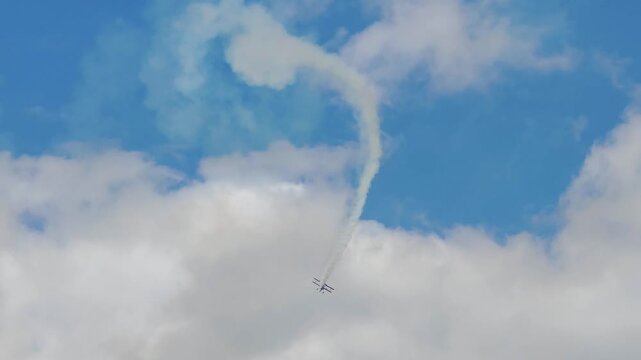 Aerobatic stunt aircrafts performing spectacular aerial maneuvers in the sky, releasing colorful smoke and fireworks. Team formation flight with white smoke trails. 4K video footage