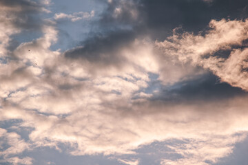 Fototapeta premium Dramatic dark storm clouds catching golden warm sunlight during sunset