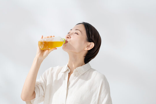 ペットボトルのお茶を飲む女性