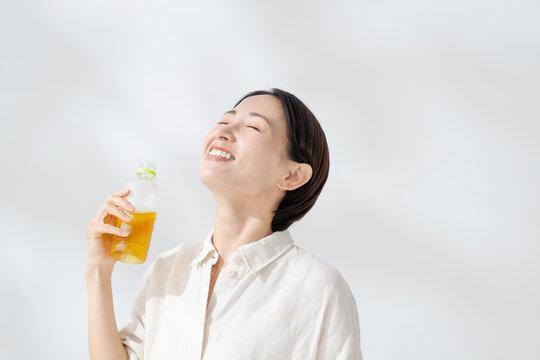 ペットボトルのお茶を飲む女性