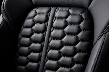 Obraz premium Black leather car features hexagonal quilting pattern. Close-up view of textured upholstery inside luxury vehicle. High-quality auto interior detail.
