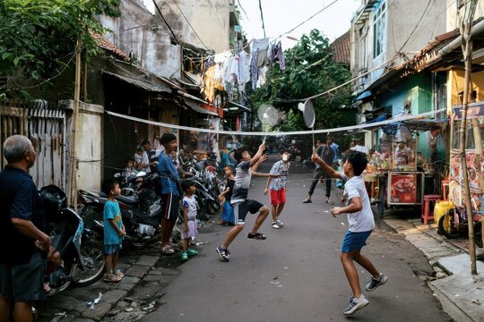 residents play badminton in a narrow street between old buildings