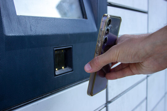 Close-up of hand scanning smartphone QR code to unlock an automated parcel locker