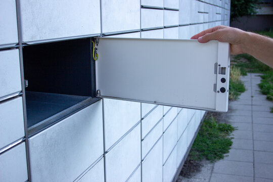 Hand fully opening an automated parcel locker compartment door to access package storage