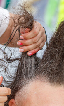 A hairdresser combs thick, dark hair with a comb.