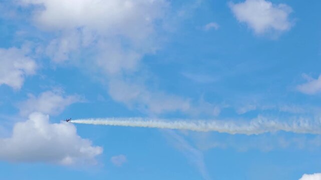 Aerobatic stunt aircrafts performing spectacular aerial maneuvers in the sky, releasing colorful smoke and fireworks. Team formation flight with white smoke trails. 4K video footage