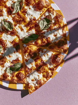 Margherita pizza slice with basil on patterned plate