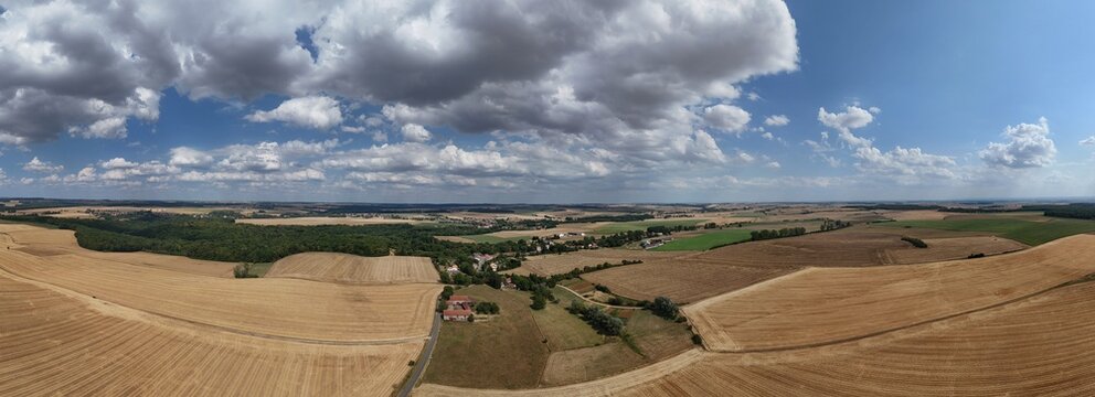 Vue a&eacute;rienne panoramique du village de Saint Supplet, en Meurthe-et-Moselle, entour&eacute; des champs apr&egrave;s la moisson en juillet 2026. Gros  nuages cumulus avec du soleil et un ciel bleu. Paysage rural