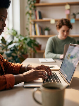 Coworkers working on laptops at table in bright office