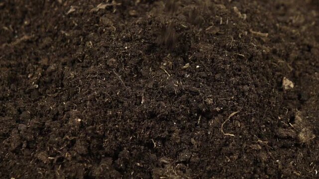 Potting soil falls into a heap of soil substrate, top view, slow motion, background