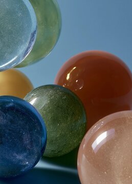 Close-up of a group of colorful spheres. there are six spheres in total, each with a different color - blue, green, orange, and pink.