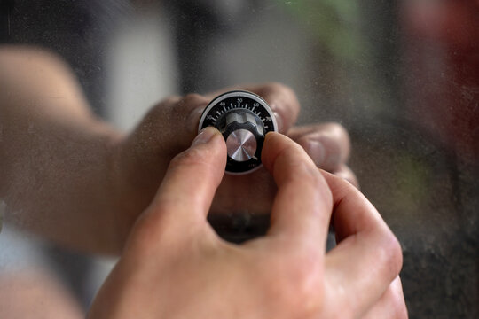 Hands adjusting a round control knob with scale markings, fine tuning settings on equipment panel.