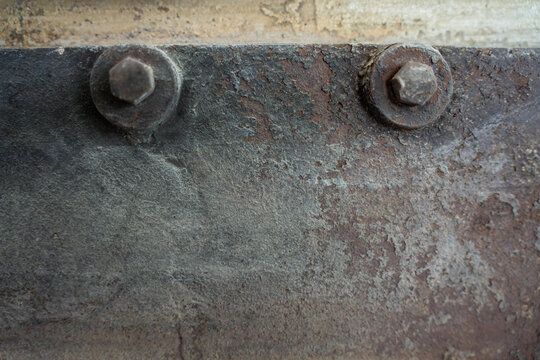 Two heavy hex bolts with washers mounted on weathered rusty metal plate surface of industrial machinery casing.