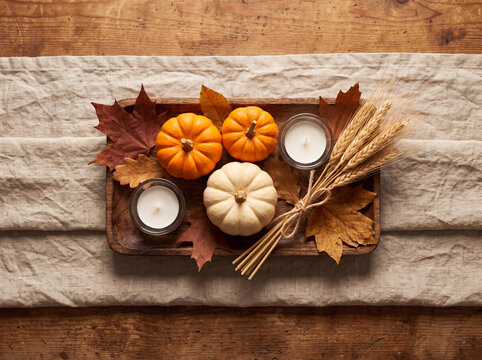 Overhead autumn centerpiece tray with mini pumpkins candles wheat and maple leaves