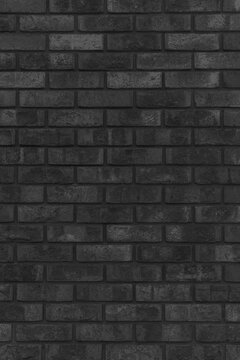 A black brick wall texture with a rustic and dark textured background. A vertical surface of aged masonry blocks with vintage industrial interior design elements.