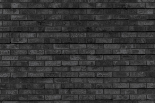 A black brick wall texture with a horizontal pattern of aged masonry blocks. A dark textured background for a rustic and vintage industrial loft interior design.