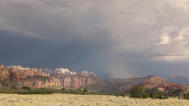 Lightning strikes the mountains of Zion National Park, Utah USA during a summer thunderstorm while sunshine breaks through the clouds and lights the rugged cliffs of West Temple Mountain, seen from th