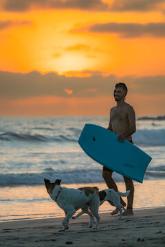 Surfer with board and dogs at Santa Elena sunset