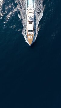 Aerial overhead view of an ultra modern luxury yacht cruising over calm ocean with speed