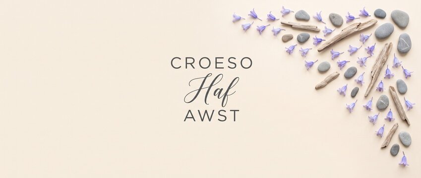 Croeso Haf Awst Welsh summer banner featuring driftwood, pebbles, and purple flowers on a minimal beige background for August greetings, seasonal marketing, spa headers, and web copy space.
