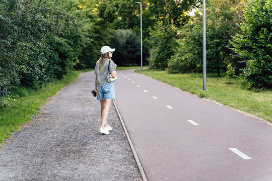Woman walking along bicycle path in summer city park