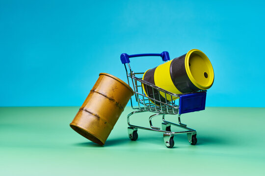 Shopping cart with industrial barrels on colored background