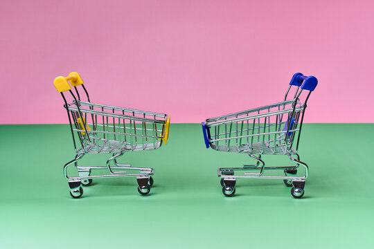 Two miniature shopping cart facing each other on color