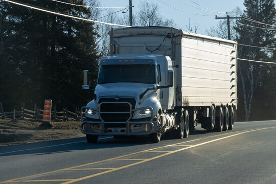 Quebec, Canada, 24 April 2026 : An International semi truck with a trailer drives on a rural road under a clear sky.