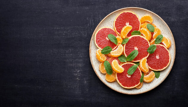 Freshly sliced grapefruit and mandarin orange segments with green mint leaves on a plate