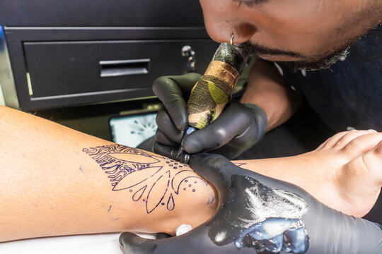 Tattoo artist working on instep foot tattoo in studio