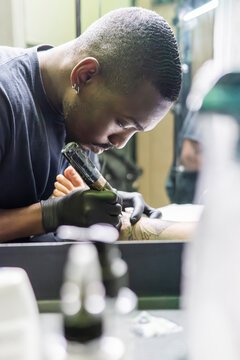 Tattoo artist using machine to ink client in studio