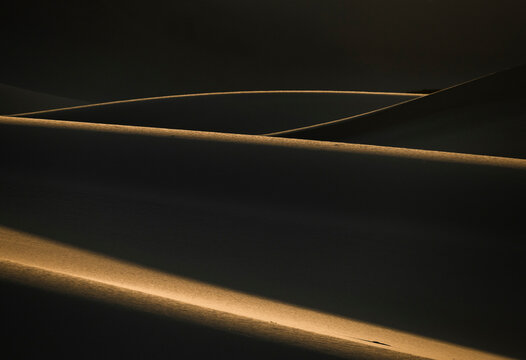 Golden light on dark sand dunes in Death Valley desert