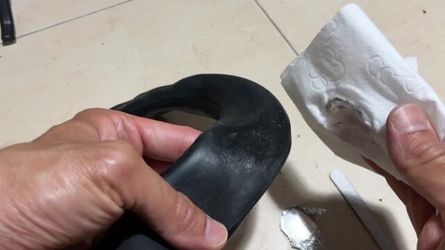 Closeup of cleaning and degreasing an electric scooter inner tube before applying a puncture repair patch during tire maintenance