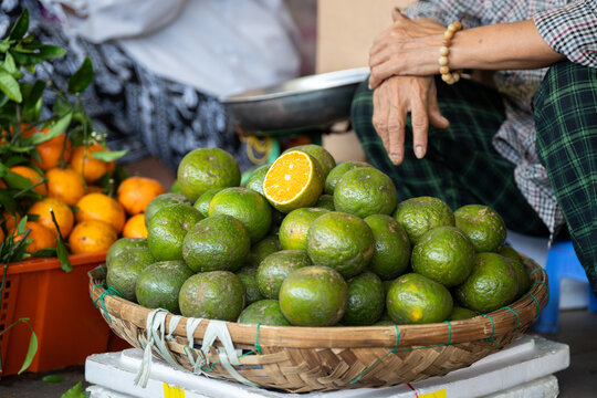 Ripe fresh green tangerines exotic fruits in basket on display selling at street food market, local vendor at stall offering tropical fruits for customers, wholesale of organic tangerines outdoors.