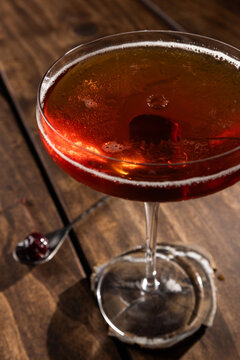 Closeup of a drop on top of a whiskey manhattan served on a rustic wooden background