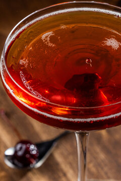 Closeup of a drop on top of a whiskey manhattan served on a rustic wooden background