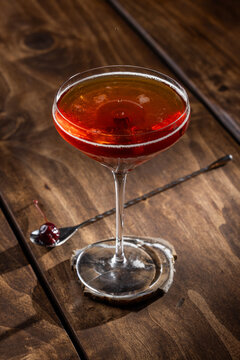 Closeup of a drop on top of a whiskey manhattan served on a rustic wooden background