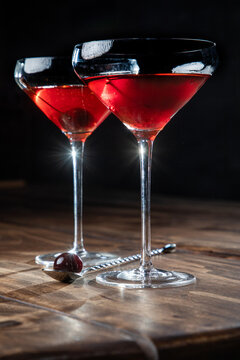 Two whiskey manhattans served with a cherry on a rustic wooden background