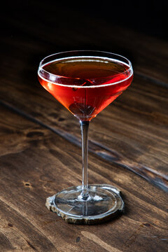 Closeup of a whiskey manhattan served with a cherry on a rustic wooden background