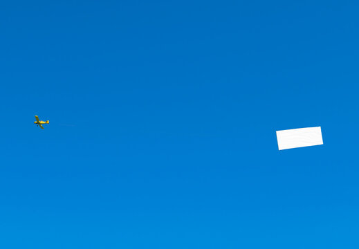 Propeller aircraft with a long white advertising banner made of fabric. Isolated on a blue background