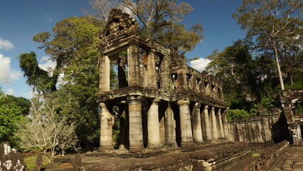 Obraz premium Ruins of a historic Khmer pavilion with classical columns under a blue sky, Angkor Wat archaeological park, Siem Reap 