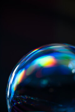 Iridescent soap bubble with rainbow reflection on black background
