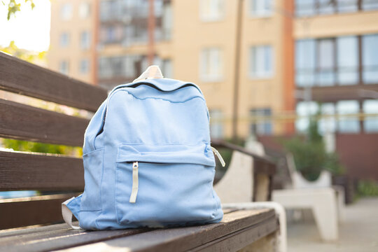 School backpack on park bench outdoors. Back to school education concept 
