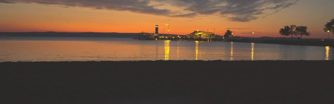 Cinematic sunset at Podersdorf pier and lighthouse, wide banner frame