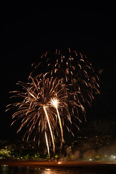 Golden fireworks burst above city skyline at night