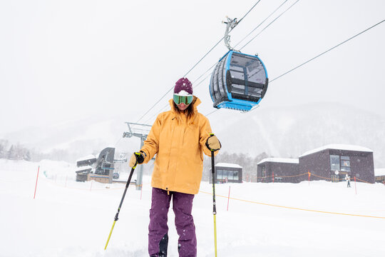 Woman skiing in snowy landscape with gondola lift
