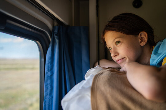 Girl looking through train window from sleeper berth