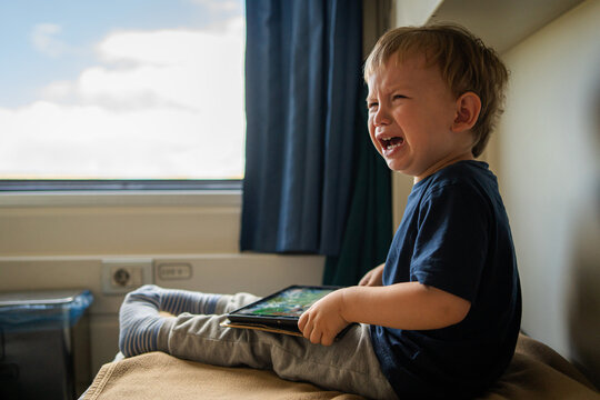Crying toddler with tablet during family train travel